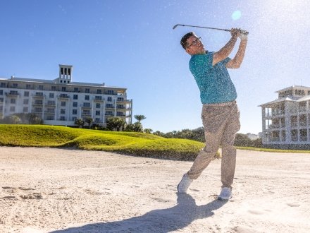 Golfer hitting a ball out of a sand trap at Kiva Dunes Golf Resort