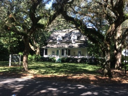 Magnolia Springs Bed and Breakfast surrounded by large oak trees in a shaded garden setting