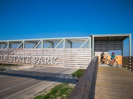 Dad and daughter biking across the pedestrian bridge in Gulf State Parl