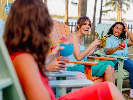 Friends sitting on Adirondack chairs by the bay at GTs waterfront restaurant in Orange Beach