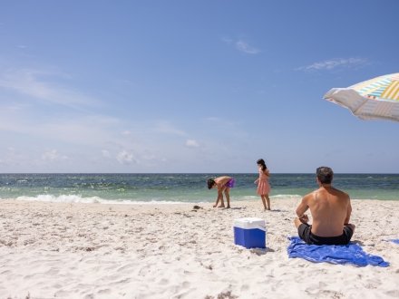 Dad watching kids play in the sand on the beach in Gulf Shores