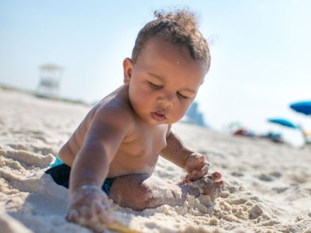 baby playing in sand at The Pavilion public beach in Gulf Shores