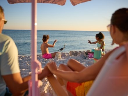 Family relaxing on the beach at sunset in Gulf Shores