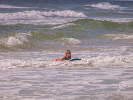 Youn girl riding a boogie board in the surf in Orange Beach