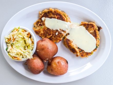 A plate of crab cakes, potatoes, and Cole slaw from Hammered Crab in Gulf Shores