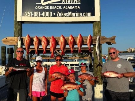 Family holding up red snapper caught on an offshore charter fishing trip at Zeke's Marina