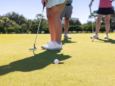 Golfer putting ball into hole on the Kiva Dunes golf course in Fort Morgan