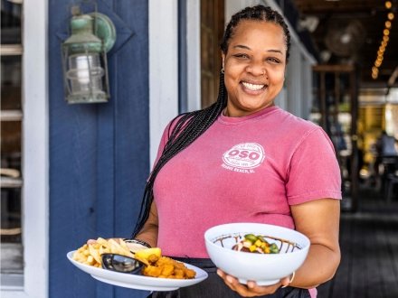 Smiling waitress serving food at OSO waterfront restaurant in Orange Beach