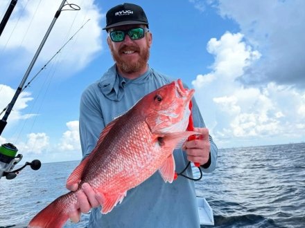 Angler holding a red snapper caught while on an offshore fishing charter in Orange Beach