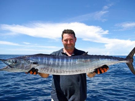 Man holding a wahoo caught while offshore fishing