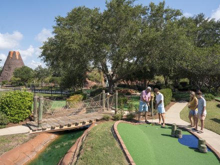 Family playing mini golf at Adventure Island putt putt course in Orange Beach