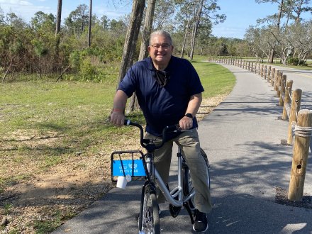 Man using the free bike rentals in Gulf State Park to explore paved nature trails in Gulf Shores