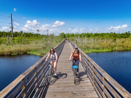 Friends biking on a boardwalk trail in Gulf State Park