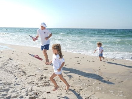 Family running on the beach with American flags