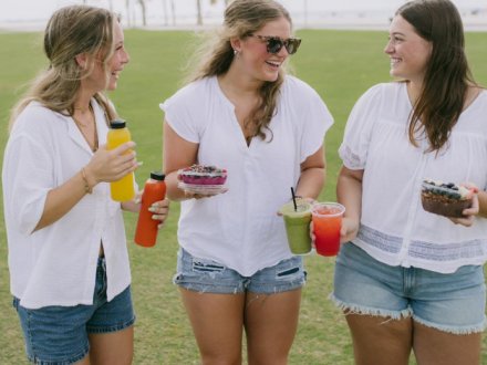 Girls with juices, smoothies, and acai bowls from Fruitful healthy restaurant in Gulf Shores