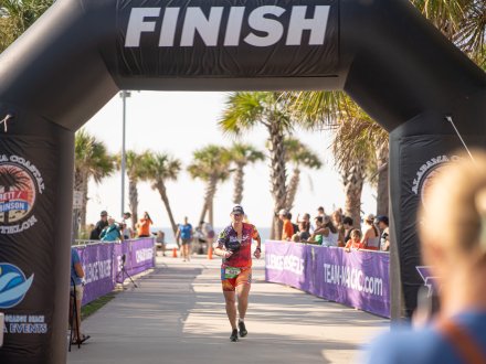 Racer crossing the finish line at the brett/robinson alabama coastal triathlon in gulf shores