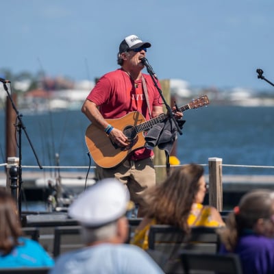 Musician performing by the water during the Annual Meeting of the Minds event in Orange Beach
