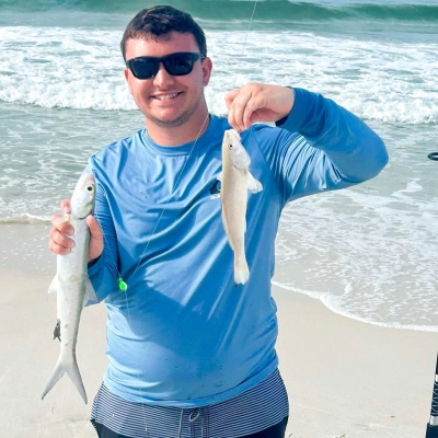 Angler holding up fish caught with surf fishing on the beach in Orange Beach