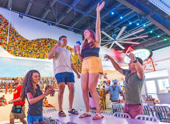 Friends dancing on the tables at The Hangout beachfront bar and restaurant in Gulf Shores