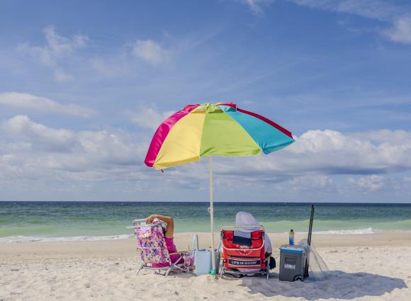 Couple relaxing under a beach umbrella on the shore in Orange Beach