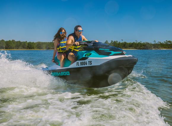 Couple riding a Jet Ski across the waves in the back bays of Orange Beach