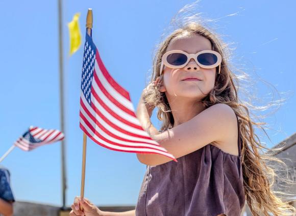 Young girl waving an American Flag on a beach boardwalk in Gulf Shores