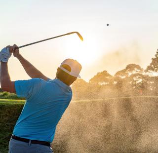 Man hitting a golf ball out of a sand pit at Kiva Dunes Golf Resort in Fort Morgan