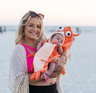 Woman holding a baby dressed in a shrimp costume at the National Shrimp Festival in Gulf Shores