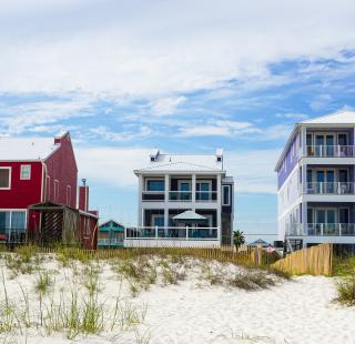 Beachfront vacation homes in Gulf Shores with colorful exteriors and balconies overlooking the white sand beach.