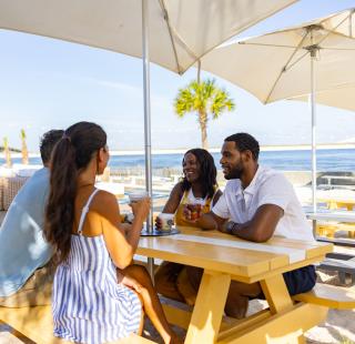 A group of friends enjoying a meal and drinks together during their vacation to Alabama's Beaches