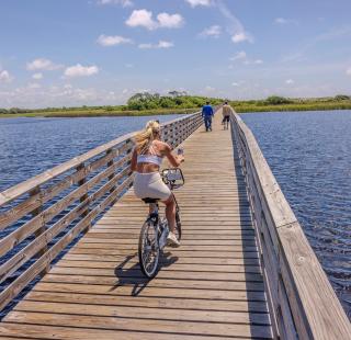 Woman riding a bike on a boardwalk along the Hugh. S. Branyon Backcountry Trail