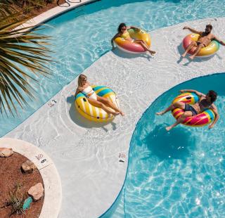 Friends floating in the lazy river at Beach Village Resort beach house community in Orange Beach