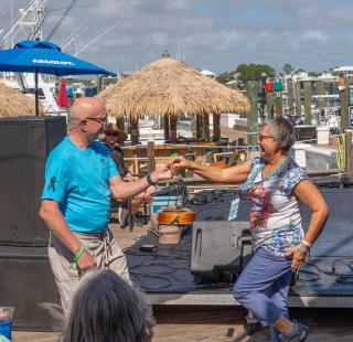 Couple dancing to live music at Zeke's waterfront restaurant during Meeting of the Minds in Orange Beach