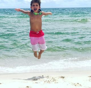 little boy jumping in the surf orange beach