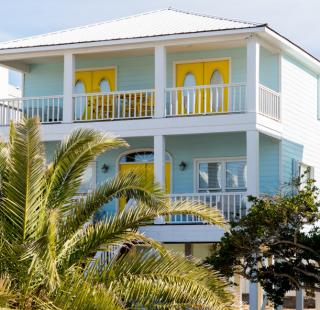 Colorful beach rental in Orange Beach, Alabama, with bright yellow doors, balconies, and palm trees in the foreground