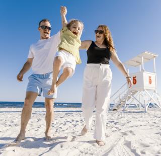 Mom, dad, and daughter making memories while walking along the beach in Orange Beach, Alabama