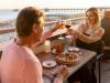 Couple cheering wine glasses at dinner on the outdoor deck at Perch fine dining restaurant in Gulf Shores