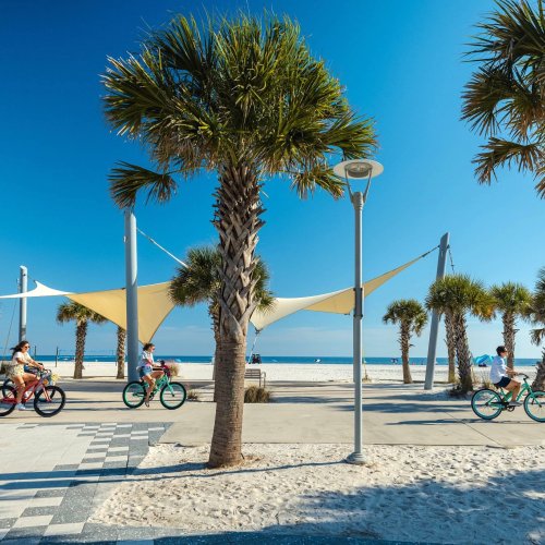 Friends riding bikes along the beach at Gulf Place in Gulf Shores